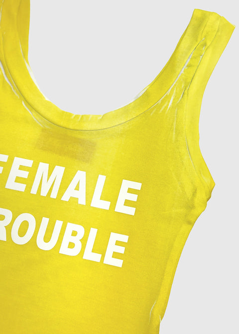 Yellow tank top with 'FEMALE TROUBLE' text on a light gray background